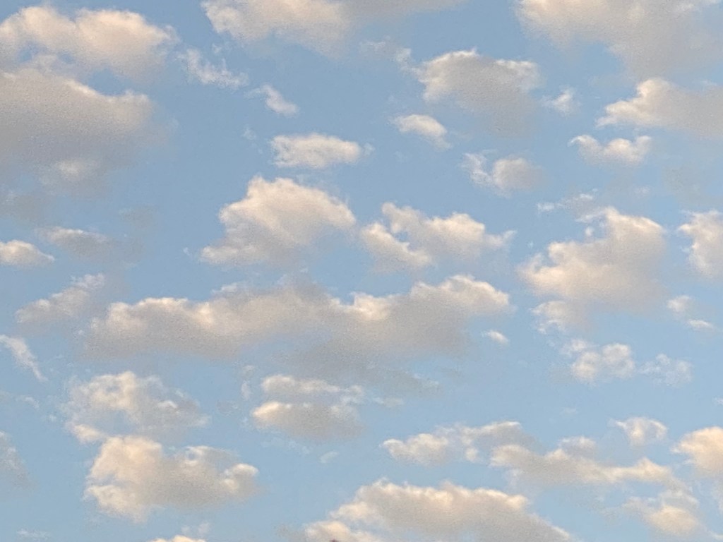 A blue sky’s beauty is enhanced by fluffy clouds.